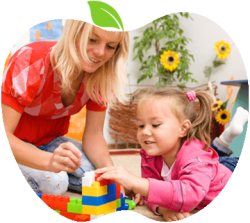 qualifiedteachersofeyeschildcare Woman and young girl playing with colorful interlocking blocks on the floor, smiling during a game together.