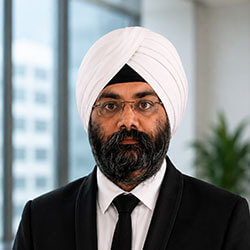 Portrait of a man wearing a white turban, glasses, and a black suit with a tie in an office. (head-and-shoulders)